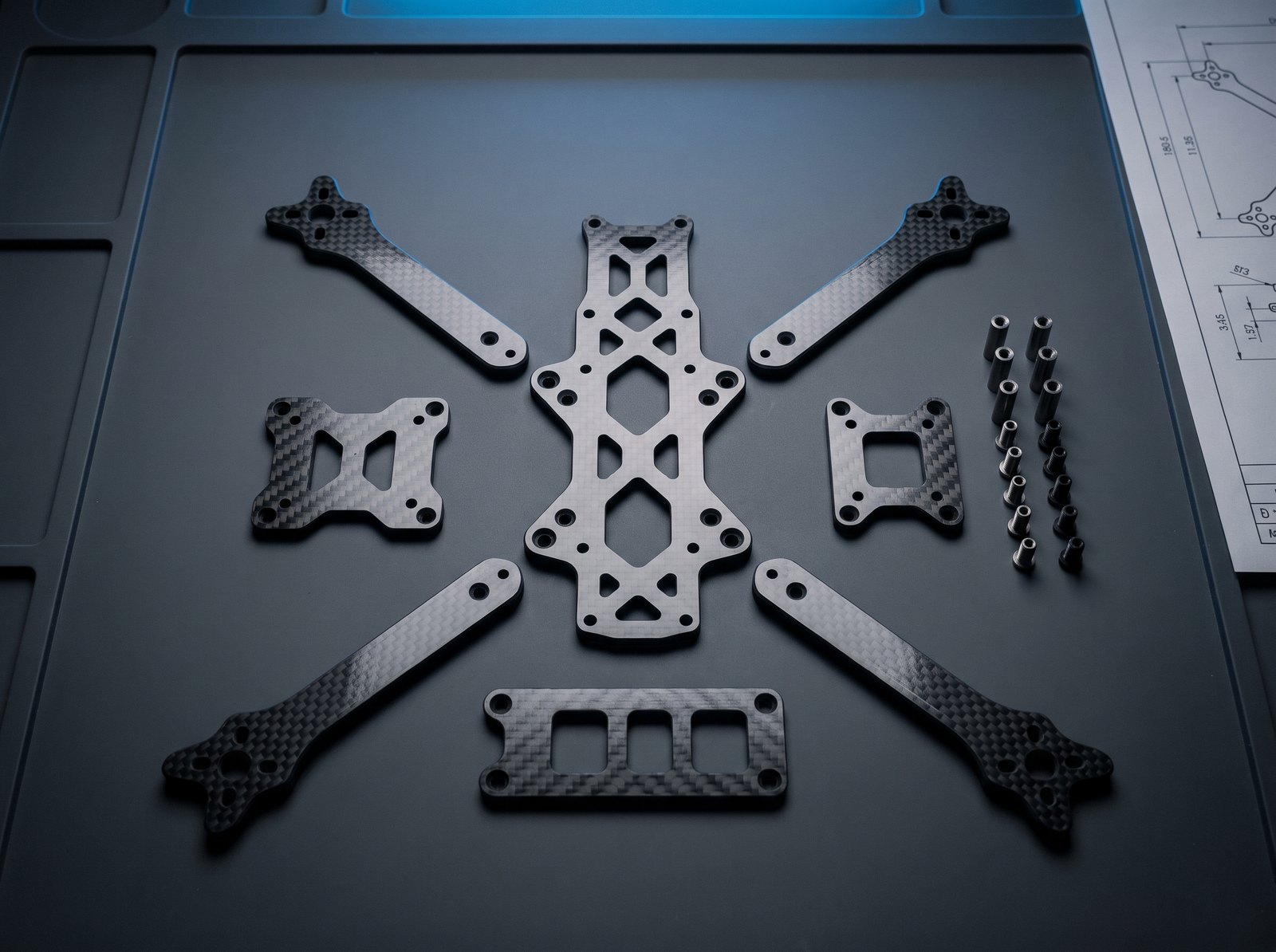 Precut carbon fiber FPV airframe kit — plates, arms, and mounts arranged assembly-ready